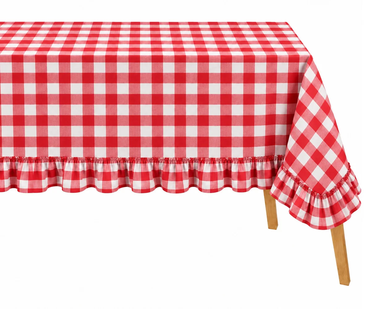 Red and white gingham checkered tablecloth with a ruffled hem and folded back corner, shown on a table with wooden legs against a white background.