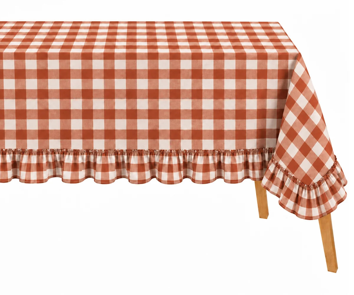 A rectangular table covered with a red and white gingham checkered tablecloth featuring a ruffled hem and matching ruffled sleeve edge, shown on a light wood table against a white background.
