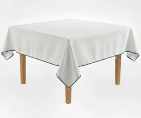 White cotton tablecloth with green piping trim on rectangular dining table