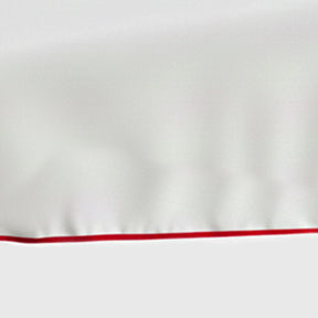 White cotton tablecloth with magenta scalloped piping trim on rectangular dining table - close up