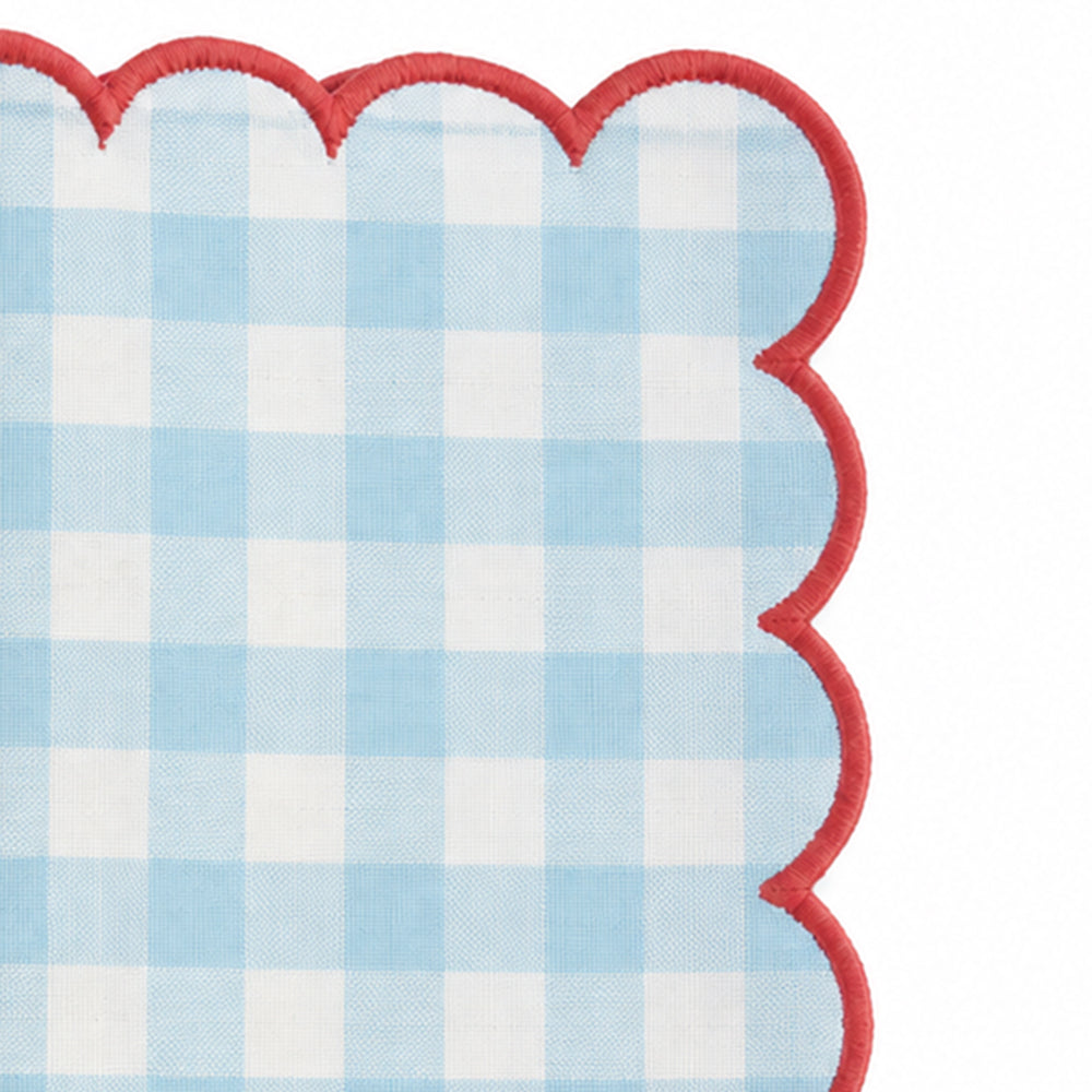 Close-up of blue and white gingham cotton dinner napkin with dark green scalloped embroidered edge.