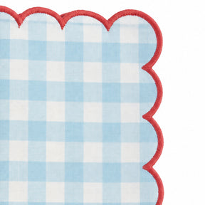 Close-up of blue and white gingham cotton dinner napkin with dark green scalloped embroidered edge.