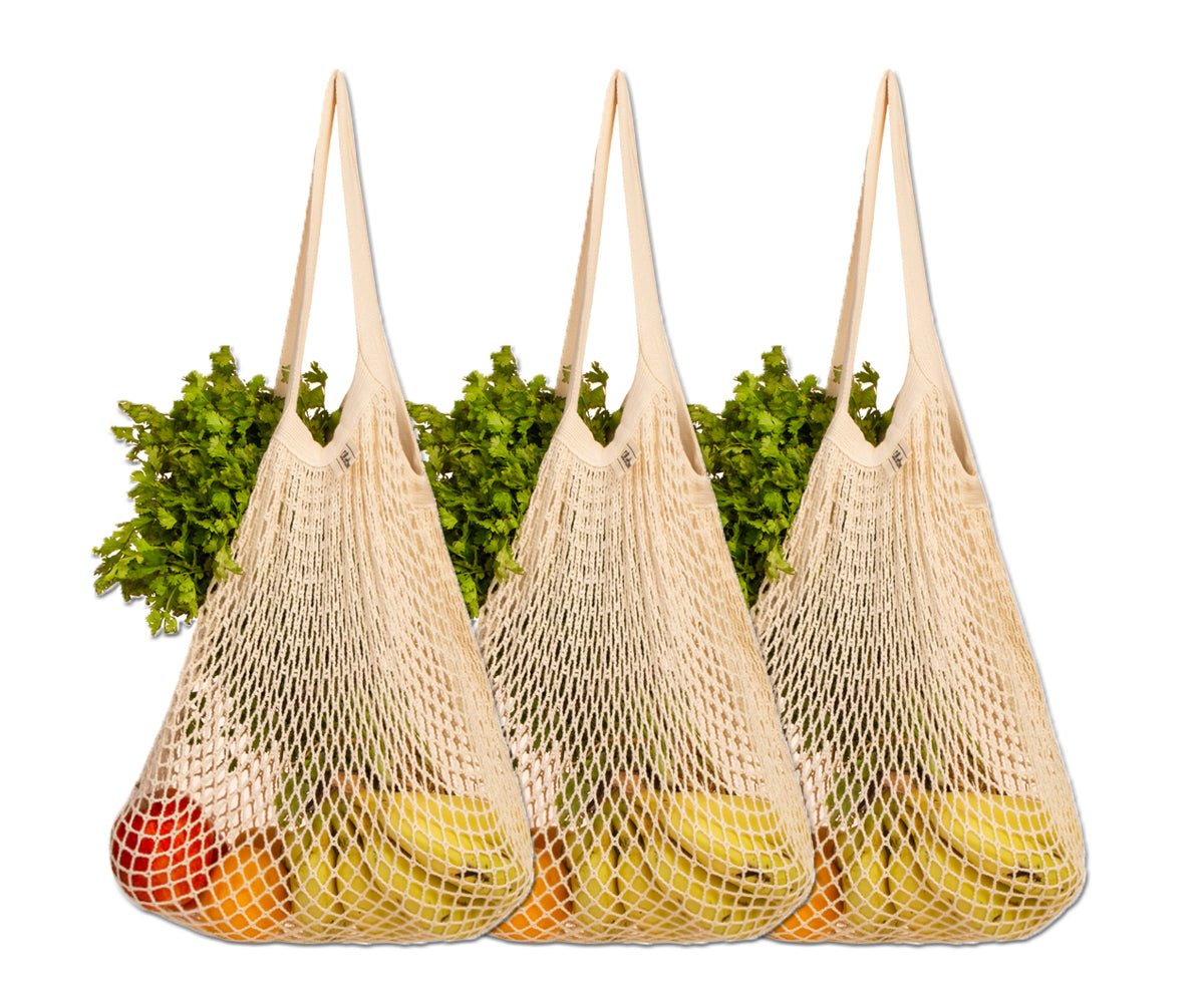 Assorted fruits and vegetables peeking from three cotton string bags