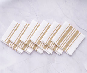 Six bistro napkins with white and gold stripes displayed on a marble surface