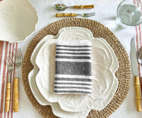 A dining table place setting with a striped linen napkin and silverware