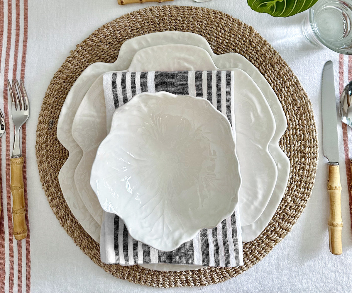 A dining place setting with a white plate and a striped linen napkin beside a fork