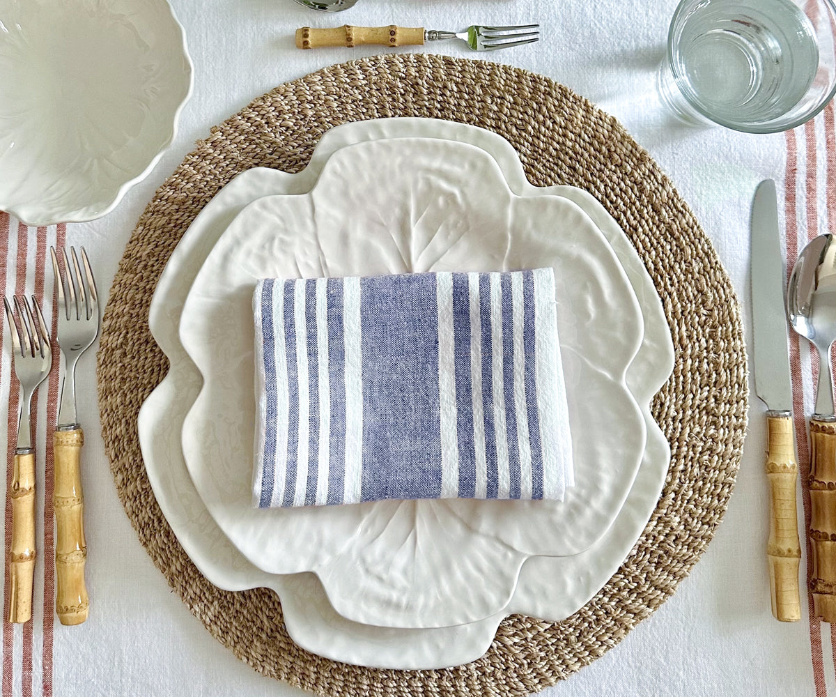 Elegant table setting featuring a blue linen dinner napkin, white plate, and bowl