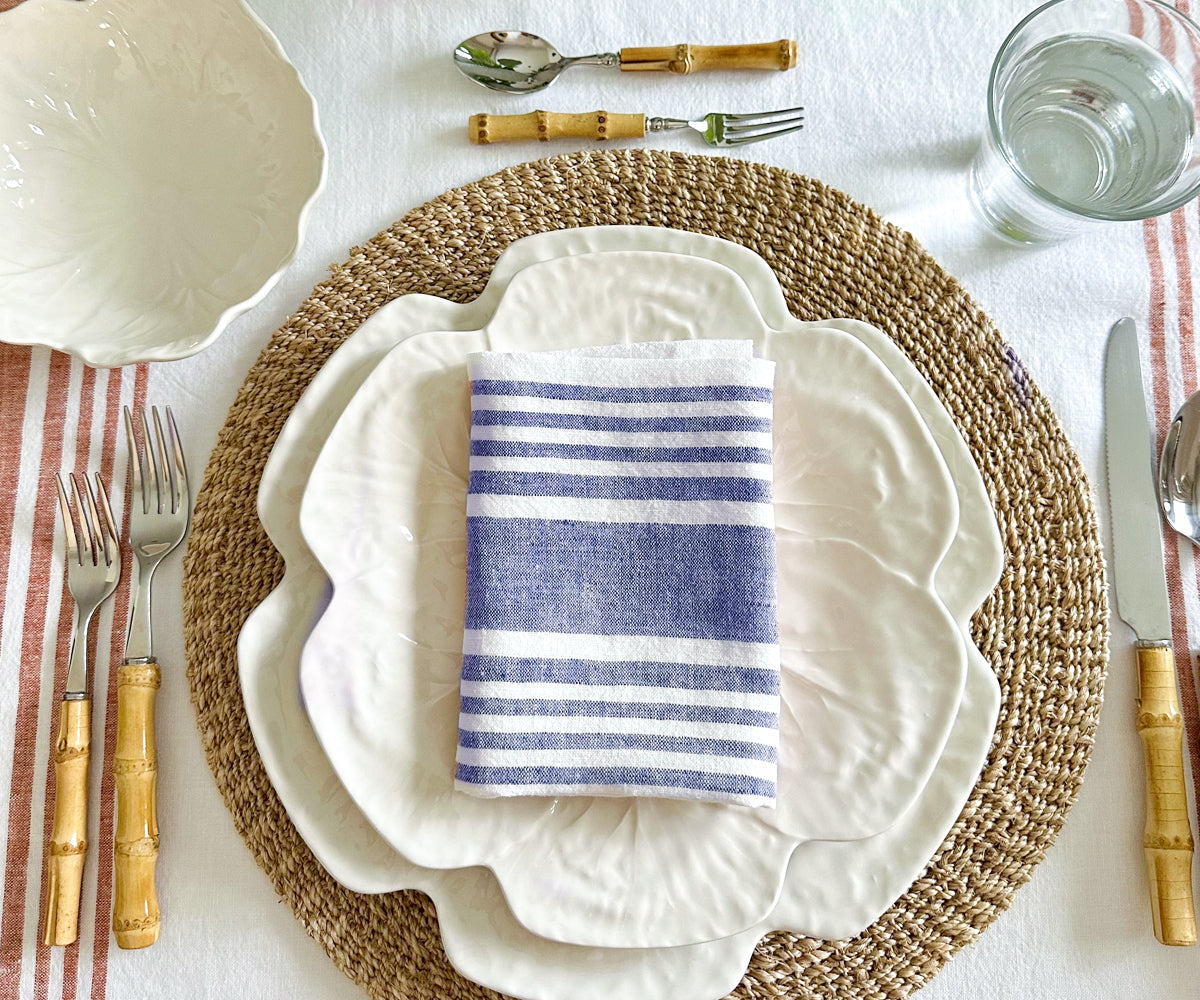 Linen dinner napkin with blue and white stripes on a set table