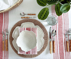 Table setting with a white plate and a linen dinner napkin with red and white stripes, accompanied by bamboo utensils