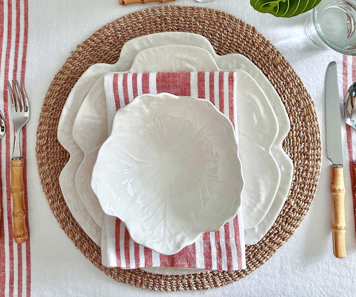 Table setting with a white plate and a linen dinner napkin with red and white stripes, accompanied by bamboo utensils