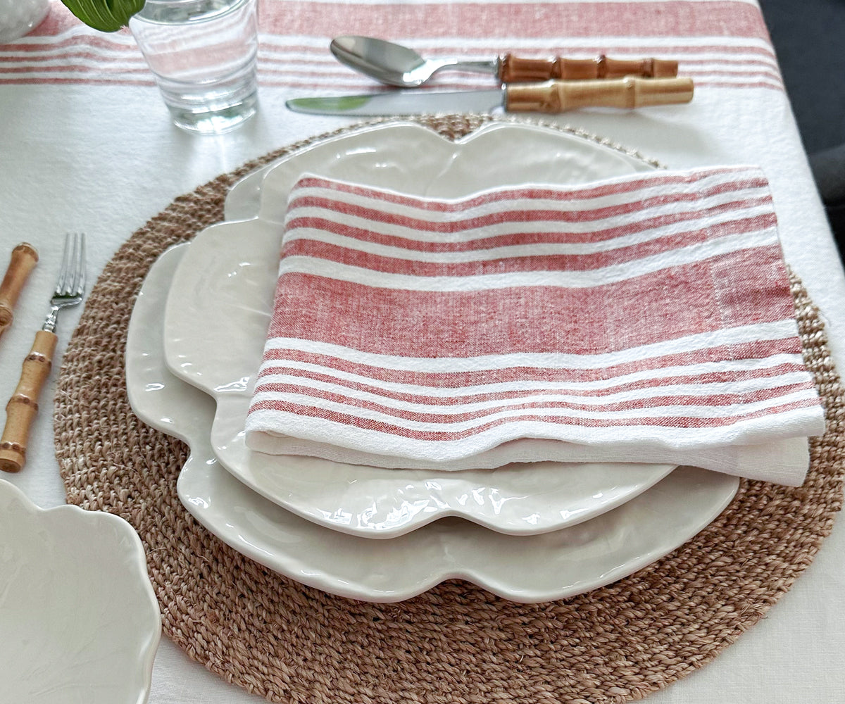 A table setting with a white dinner plate and a pink linen napkin