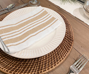 Table setting featuring a white plate and a brown bistro napkin