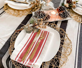 Table setting showcasing a red and white striped restaurant napkin and gold cutlery