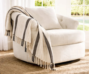 Stylish striped throw blanket arranged on a living room chair for cozy and elegant interior styling