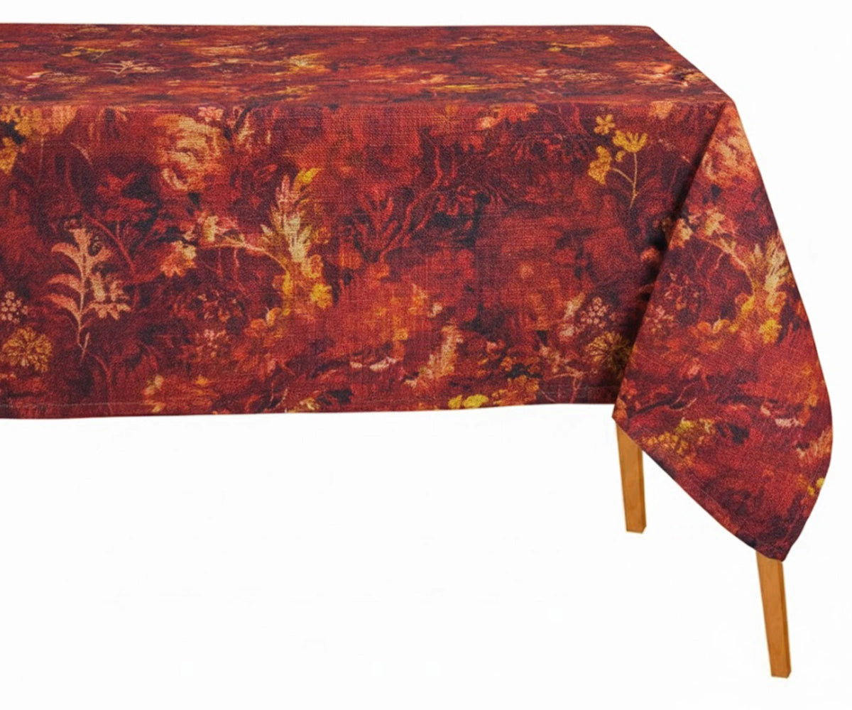 Rectangular autumn floral tablecloth in rich rust red and burgundy tones with botanical print, draped over a wooden dining table.