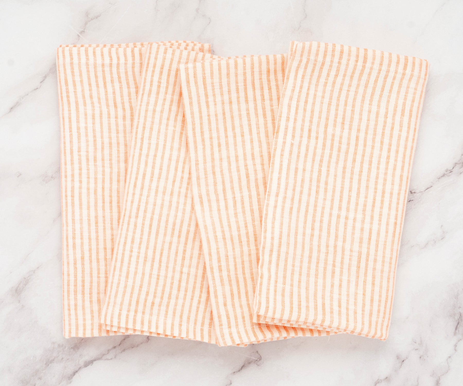 Set of 12 bright orange striped linen napkins arranged in a clean tabletop display