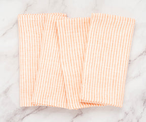Set of 12 bright orange striped linen napkins arranged in a clean tabletop display
