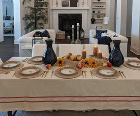 Dining room setup featuring a French tablecloth, white couch, and chairs. Farmhouse Cotton Tablecloth for Rectangles.