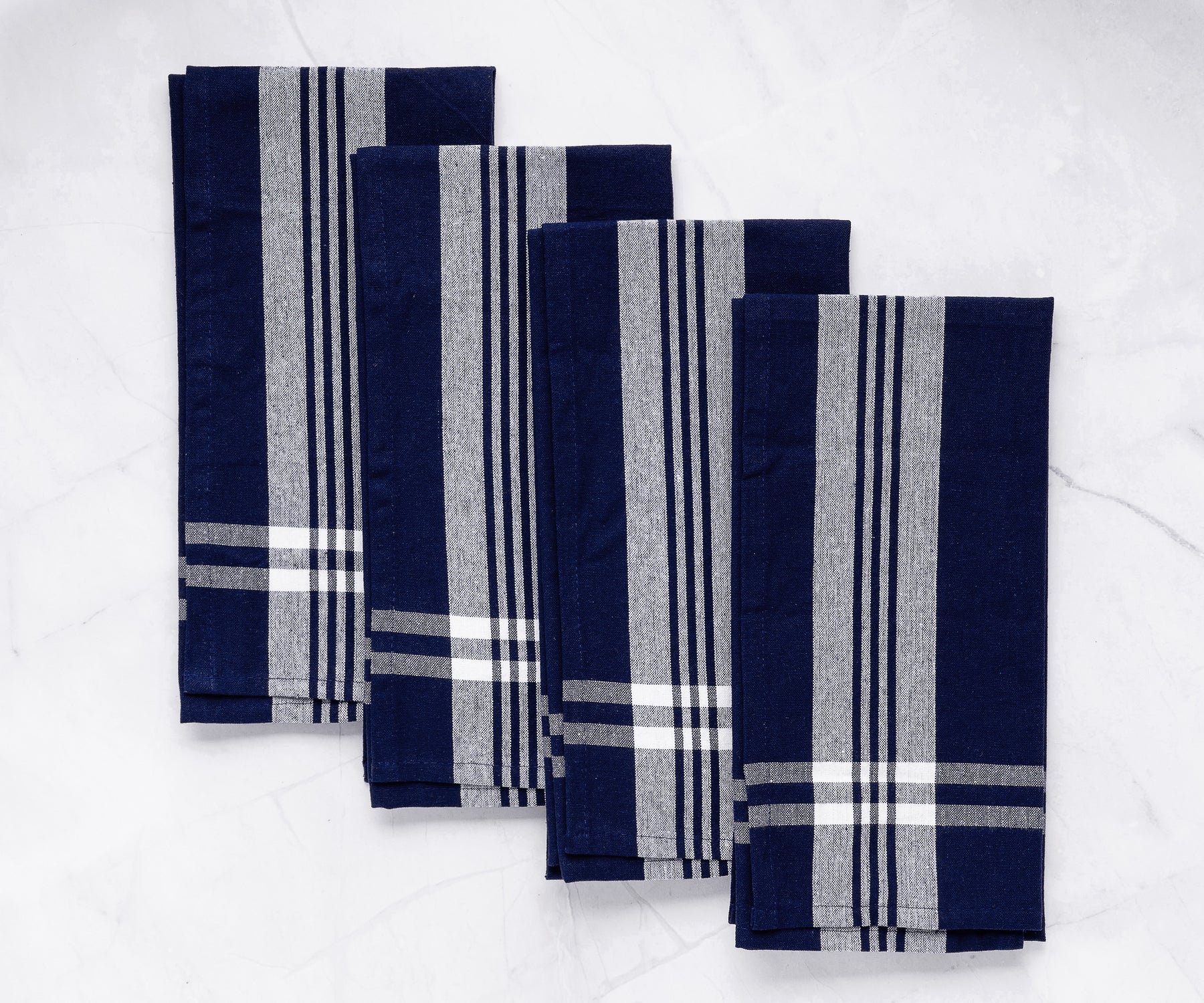 Four blue and white striped farmhouse kitchen towels arranged on a marble countertop