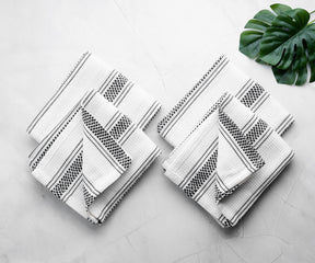 Black and white striped dish towels neatly folded and styled with a decorative leaf.