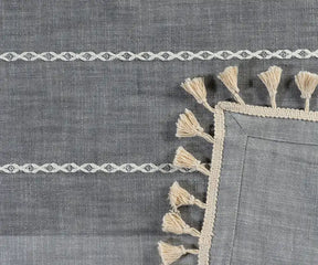 Gray fabric with white lace trim and tassels on a matching gray background