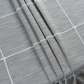 Gray striped farmhouse-style tablecloth with tassel trim on a rustic dining table