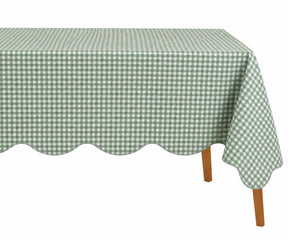 Sage green and white small checkered cotton tablecloth with a decorative scalloped edge draped over a table.
