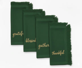 Elegant green embroidered napkins with gold lettering and fringed edges for festive table settings