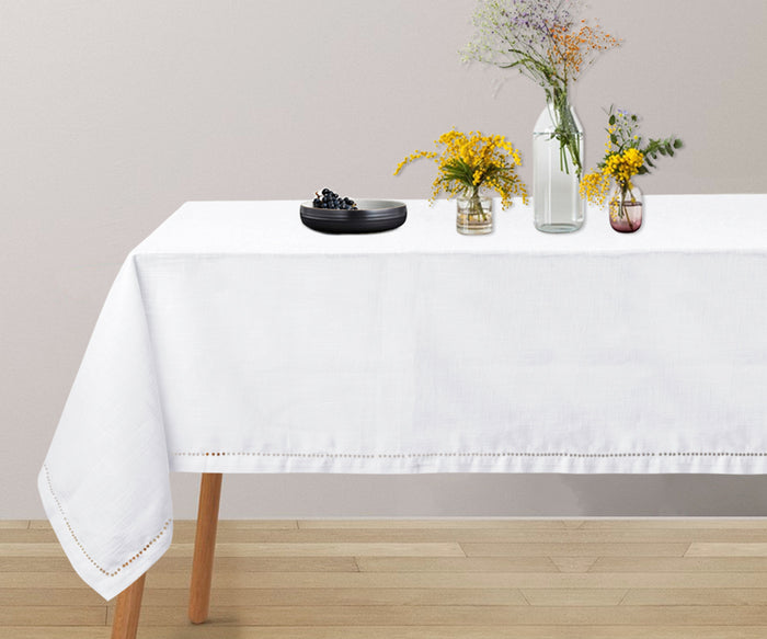 Classic white hemstitch tablecloth draped over wooden dining table
