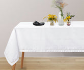 Classic white hemstitch tablecloth draped over wooden dining table
