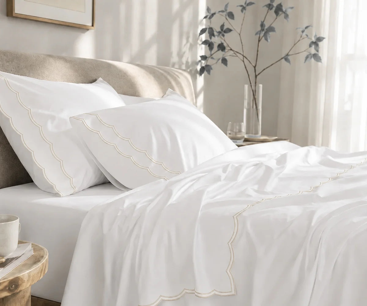 White cotton bedding set with ivory scalloped edge embroidery on pillowcases and flat sheet.