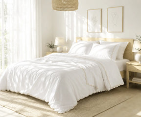 White cotton bedspread set with ivory scalloped edge embroidery styled on a bed in a bright bedroom.
