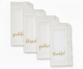 Ivory embroidered Christmas napkins with gold lettering and soft fringed edges