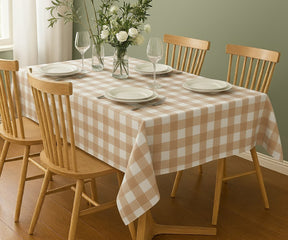 Dining table set with a checkered tablecloth, plates, and glasses in a room with wooden chairs.