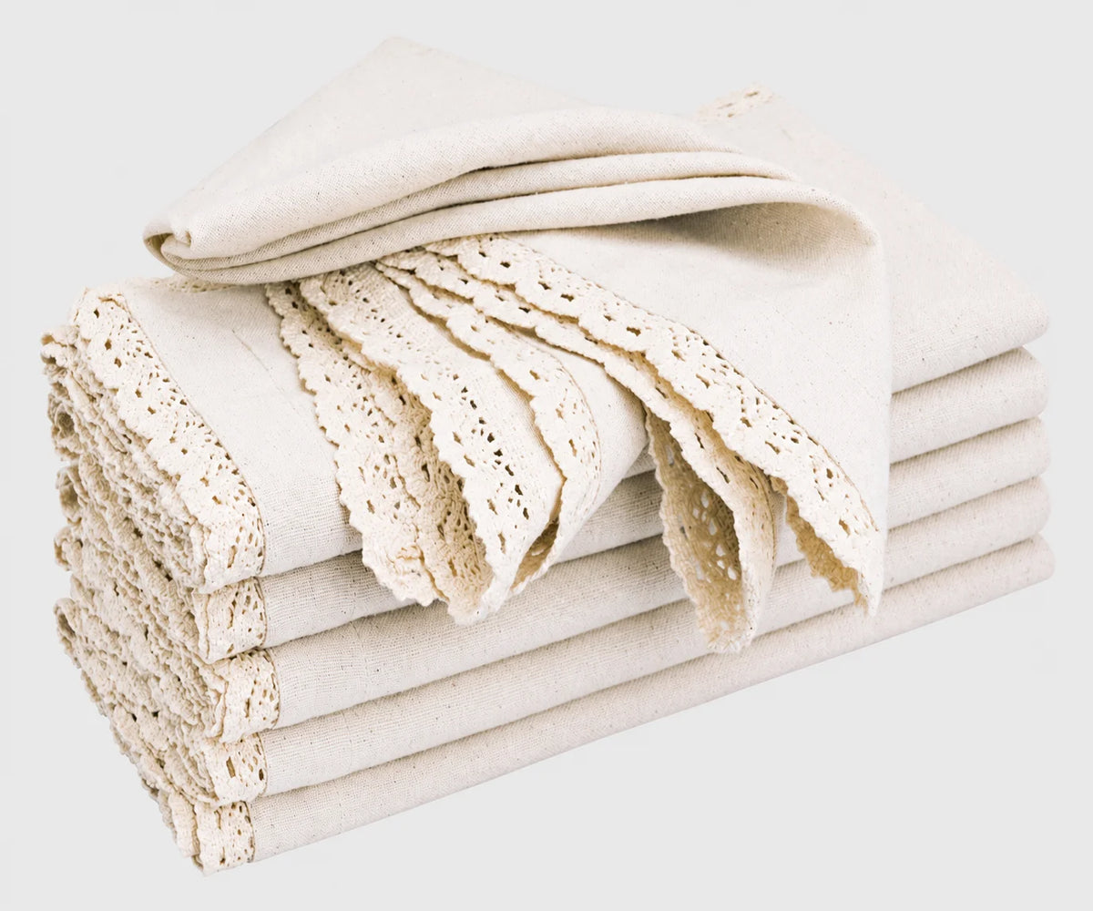 Folded natural beige cotton cloth napkins featuring delicate lace cutwork edging and decorative trim