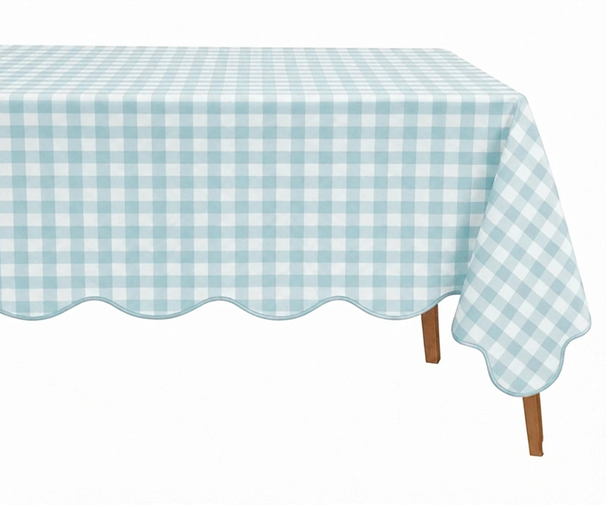 Light blue and white checkered cotton tablecloth with a decorative scalloped edge draped over a table.