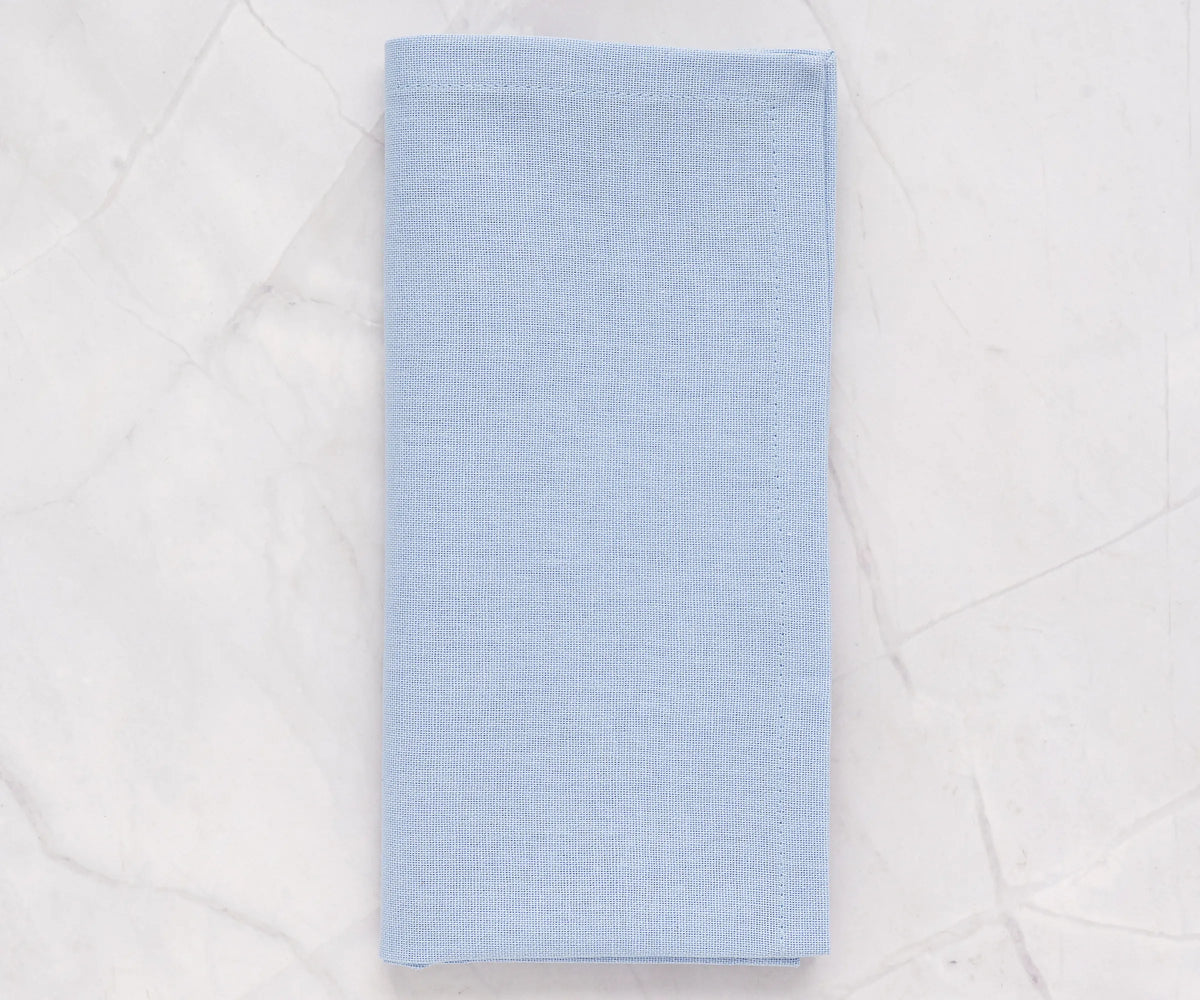 Light blue cotton cloth napkins neatly folded on a dining table