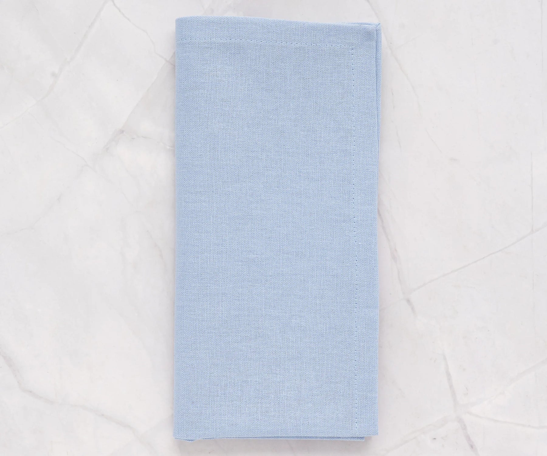 Light blue cotton cloth napkins neatly folded on a dining table