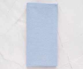 Light blue cotton cloth napkins neatly folded on a dining table