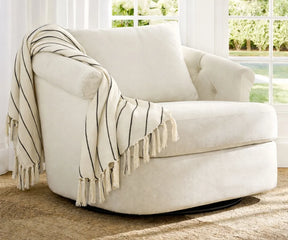 Soft striped cotton throw blanket draped over a comfortable lounge chair in a bright living room setting