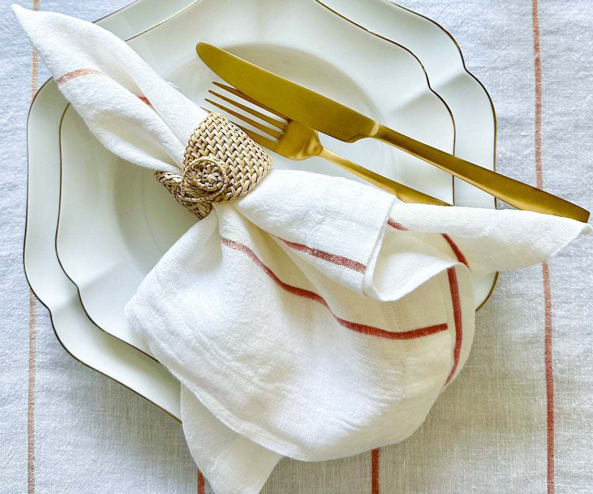 Achieve an exquisite table arrangement with dinner napkins folded using rings, elegantly displayed in a chic napkin holder, adding a touch of sophistication to your dining experience.