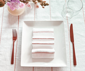 Create a sophisticated table setting by expertly folding dinner napkins with rings and showcasing them in a fashionable napkin holder.