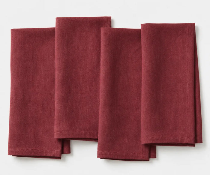 Plain burgundy linen napkin neatly folded, showing rich deep red color and smooth fabric