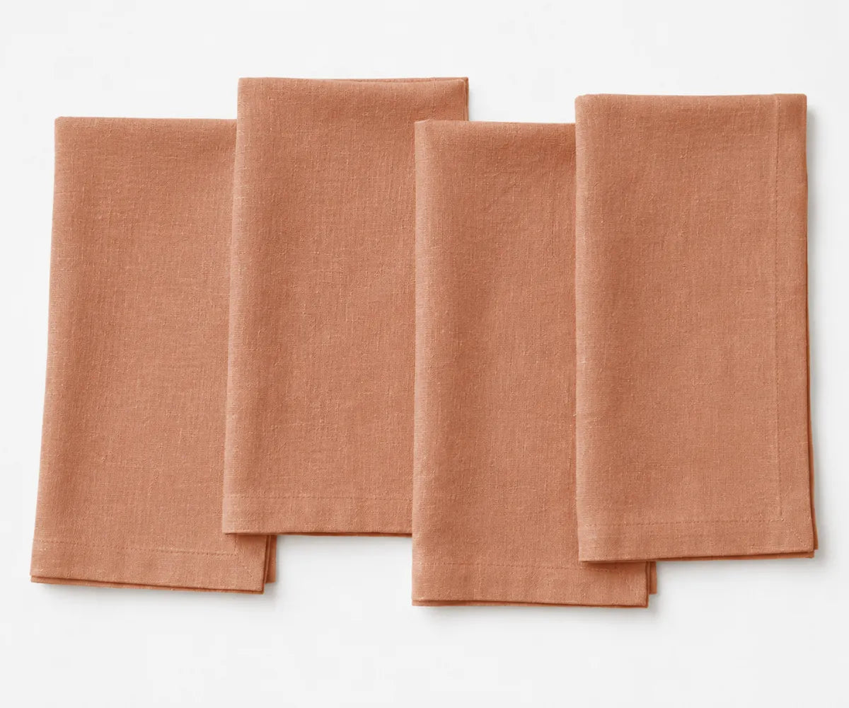 Clay-colored plain linen napkin with natural earthy tone, folded with clean stitched edges