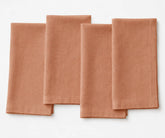 Clay-colored plain linen napkin with natural earthy tone, folded with clean stitched edges