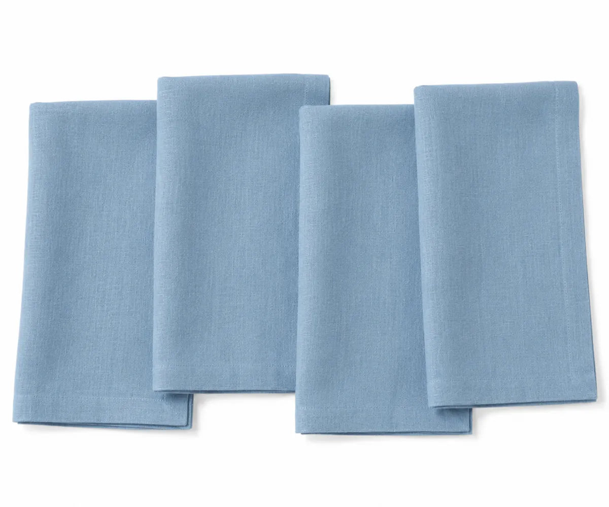 Cornflower blue plain linen napkin arranged on dining table, showing soft textured fabric