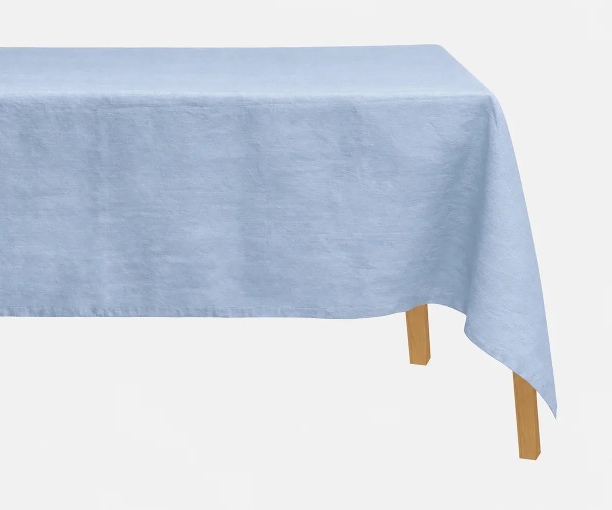 Light blue 100% European linen tablecloth styled on a rectangular dining table with elegant dinnerware