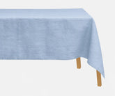 Light blue 100% European linen tablecloth styled on a rectangular dining table with elegant dinnerware