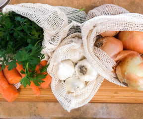 Reusable mesh produce bag on a cutting board with fresh produce