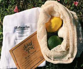 "A set of reusable produce bags in various sizes next to a grocery basket."